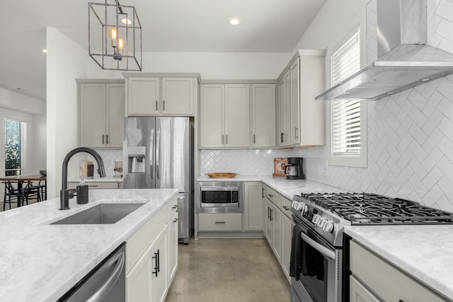 kitchen with stainless steel appliances, concrete floors, a sink, wall chimney exhaust hood, and pendant lighting