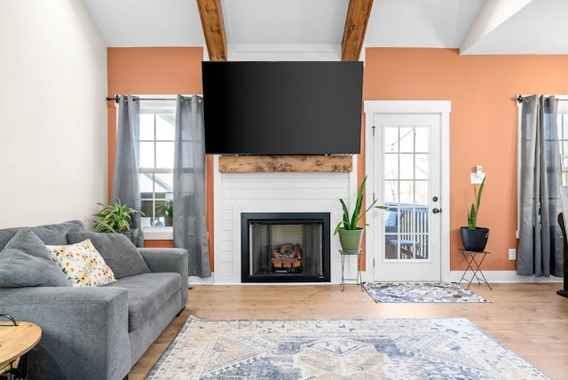 living area with beamed ceiling, a fireplace, and wood finished floors