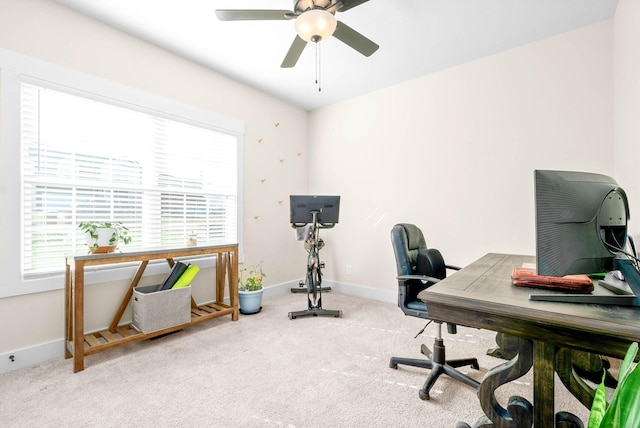 carpeted office space with a ceiling fan and baseboards