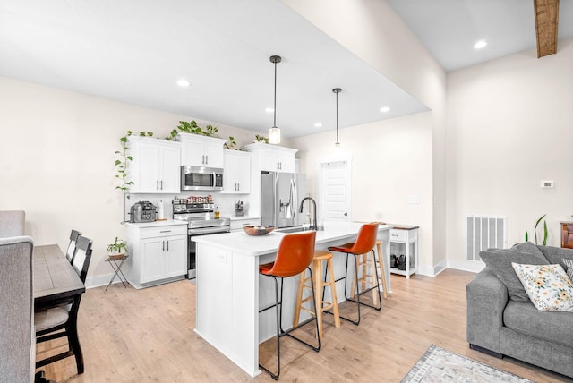 kitchen featuring stainless steel appliances, visible vents, a kitchen breakfast bar, and white cabinetry