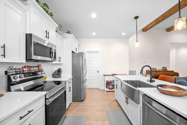 kitchen with white cabinets, appliances with stainless steel finishes, light countertops, light wood-type flooring, and a sink