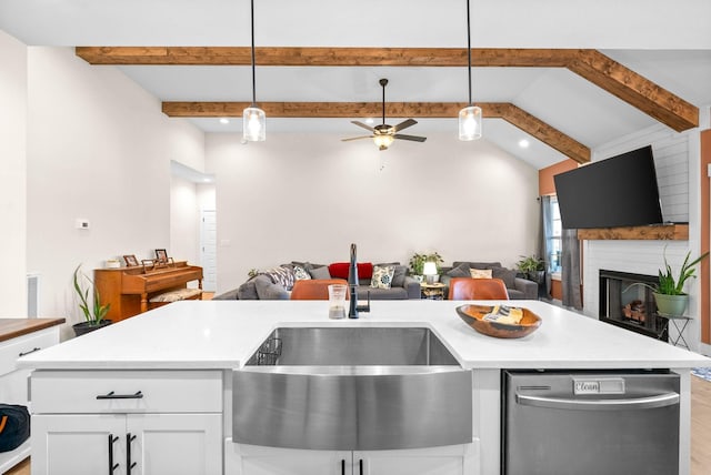 kitchen featuring open floor plan, light countertops, dishwasher, and a fireplace