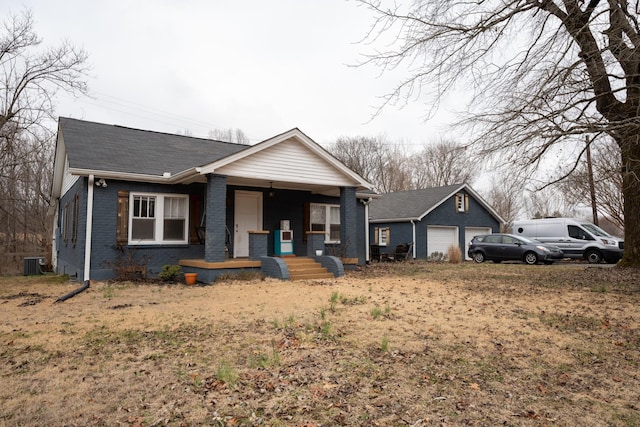 bungalow-style house with a garage, an outbuilding, central air condition unit, a porch, and brick siding