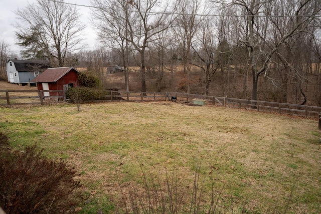 view of yard featuring a storage shed, a fenced backyard, and an outbuilding