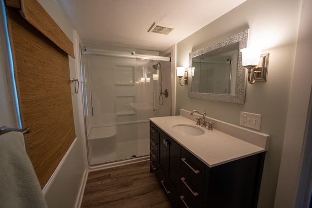 bathroom featuring wood finished floors, a stall shower, vanity, and visible vents