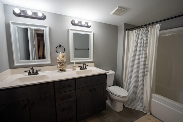 full bath with toilet, double vanity, a sink, and visible vents