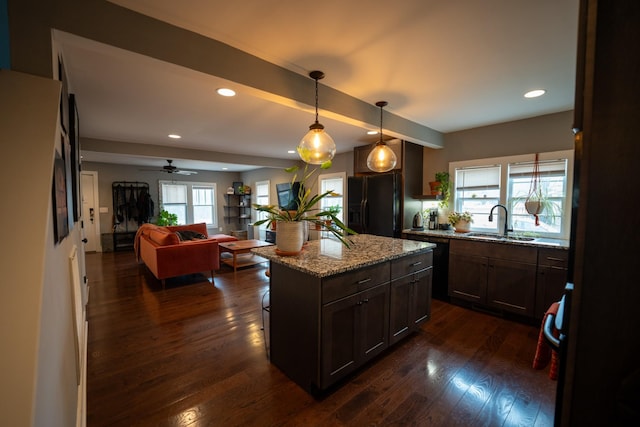 kitchen featuring a sink, open floor plan, light stone countertops, dark wood-style floors, and black refrigerator with ice dispenser