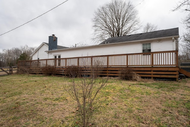 rear view of house featuring a chimney, a lawn, a deck, and fence