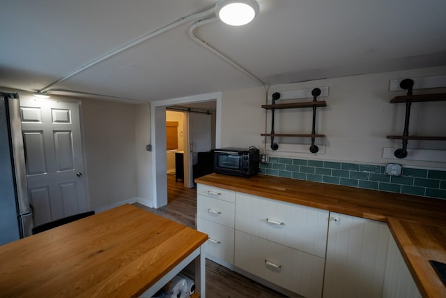 kitchen with tasteful backsplash, butcher block counters, open shelves, and a barn door