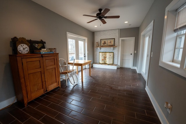 interior space with recessed lighting, wood finish floors, a ceiling fan, baseboards, and a brick fireplace