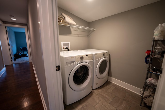 washroom with laundry area, stone finish flooring, washer and clothes dryer, and baseboards