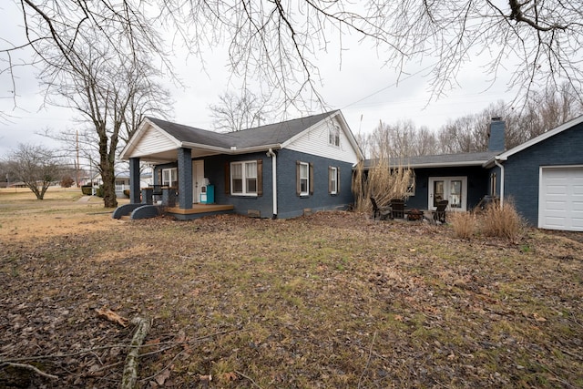 view of front facade featuring an attached garage, french doors, brick siding, and a porch