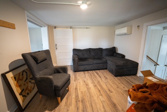 living area with a wall mounted air conditioner, light wood finished floors, and a barn door