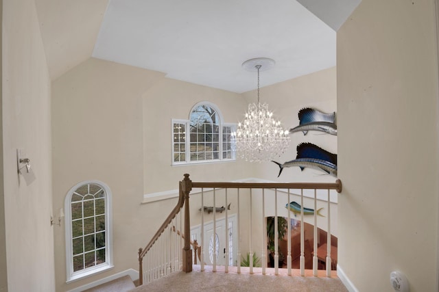 stairway with carpet floors, vaulted ceiling, and a notable chandelier