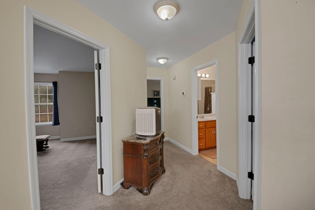 hallway featuring baseboards and light colored carpet