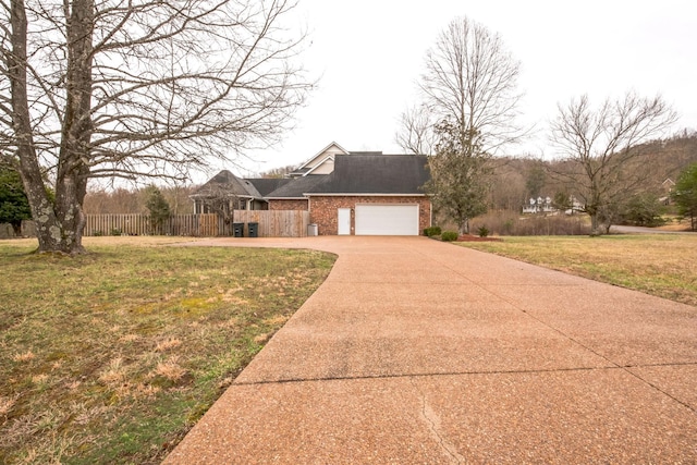 view of front facade with brick siding, concrete driveway, a front yard, fence, and a garage