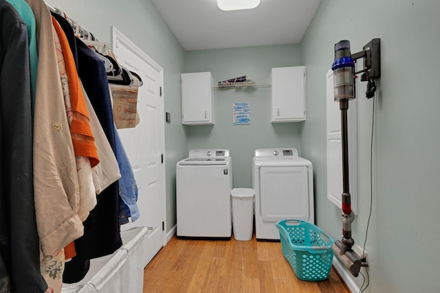 laundry room with cabinet space, washing machine and dryer, and light wood-style flooring