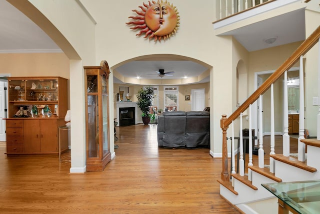 entrance foyer with light wood-type flooring, ceiling fan, a fireplace, and stairs