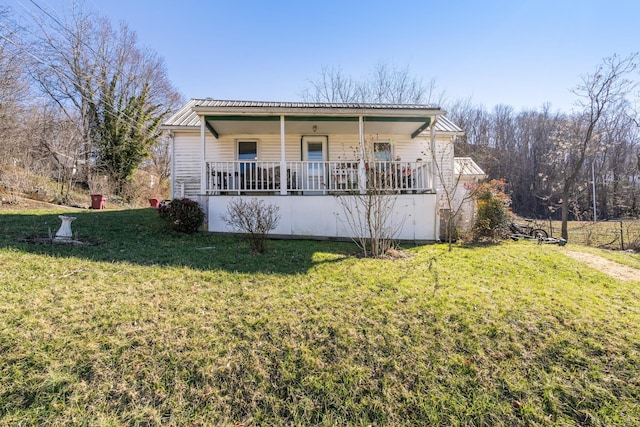 view of front of property with covered porch, metal roof, and a front yard