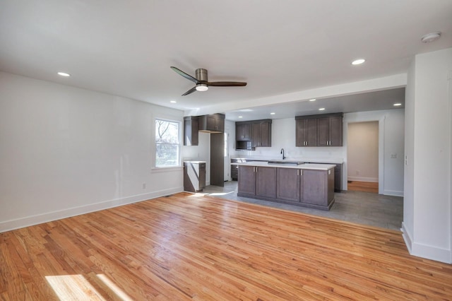 unfurnished living room featuring baseboards, a ceiling fan, light wood-style floors, a sink, and recessed lighting