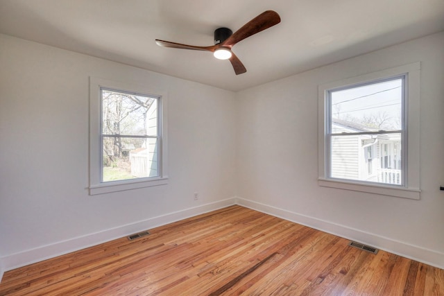 spare room featuring light wood finished floors, baseboards, visible vents, and ceiling fan