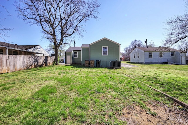 rear view of house featuring a yard, central AC, and fence