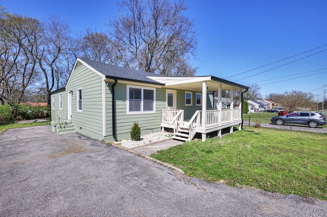 view of front of property with covered porch, a shingled roof, and a front yard