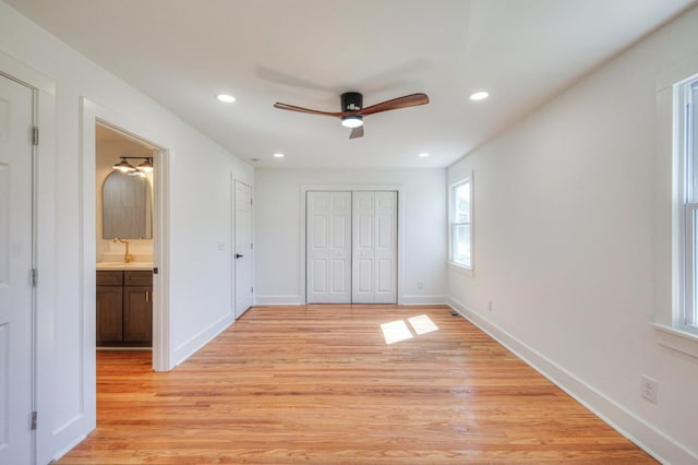 unfurnished bedroom featuring light wood-type flooring, a sink, a closet, and recessed lighting