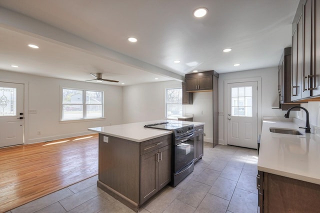 kitchen with black electric range, a healthy amount of sunlight, light countertops, and a sink