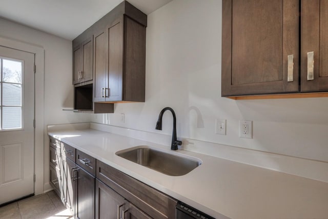 kitchen featuring light countertops, a sink, dark brown cabinetry, and light tile patterned floors