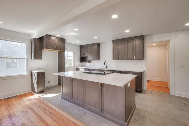 kitchen featuring recessed lighting, light countertops, visible vents, a kitchen island, and baseboards