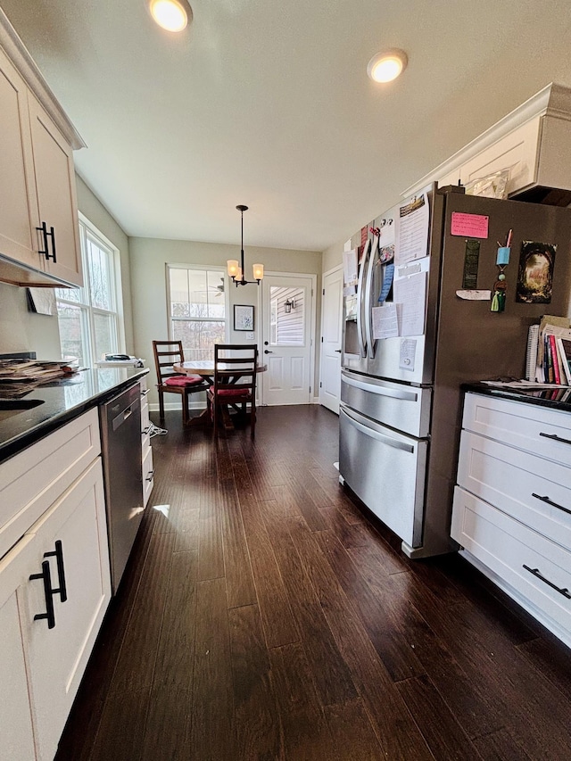 kitchen featuring appliances with stainless steel finishes, dark countertops, pendant lighting, and dark wood finished floors