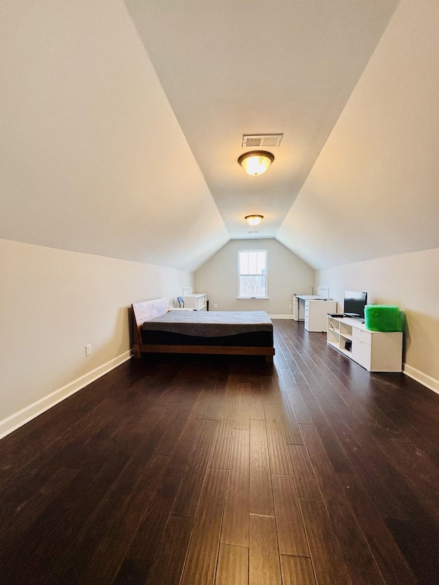 unfurnished bedroom with baseboards, visible vents, vaulted ceiling, and wood finished floors