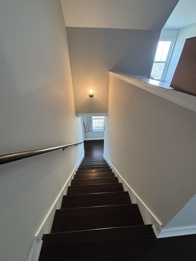 staircase with wood finished floors, a wealth of natural light, and baseboards