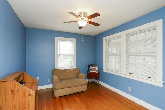 living area featuring a ceiling fan, baseboards, and wood finished floors