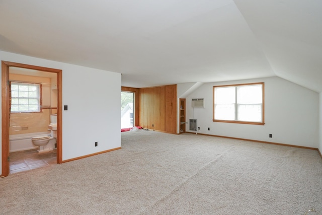 bonus room with lofted ceiling, a wall mounted AC, plenty of natural light, and light colored carpet