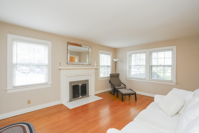 living area featuring a fireplace, baseboards, and wood finished floors