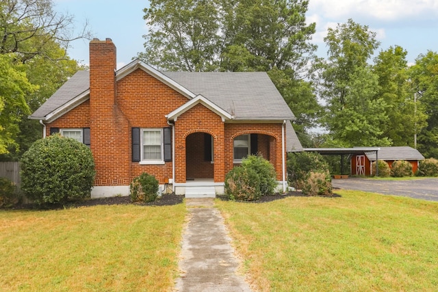 bungalow with a chimney, a front lawn, a carport, and brick siding