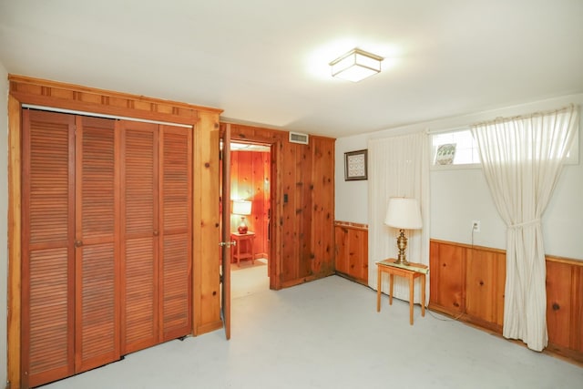 living area featuring wood walls, visible vents, and a wainscoted wall