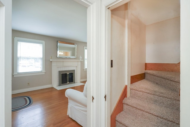 stairway with a fireplace, baseboards, and wood finished floors