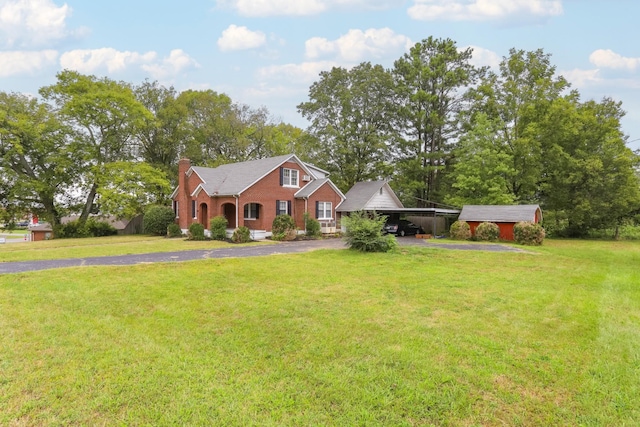 view of front of home with driveway, a chimney, and a front lawn