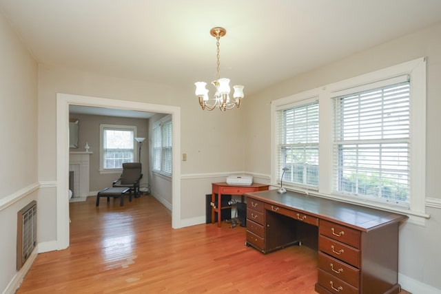 home office featuring light wood-style floors, baseboards, a fireplace, and a chandelier