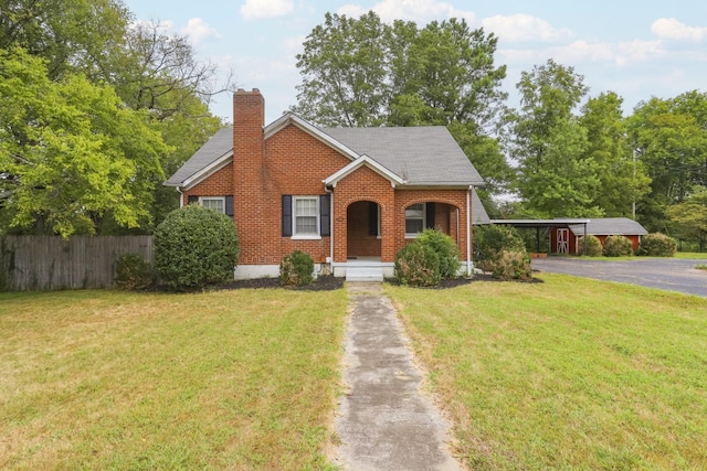 view of front of home featuring a front yard, brick siding, fence, and a chimney