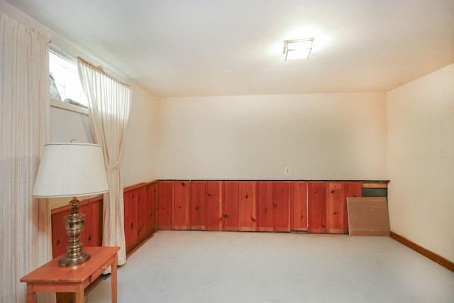 spare room with concrete flooring and wainscoting