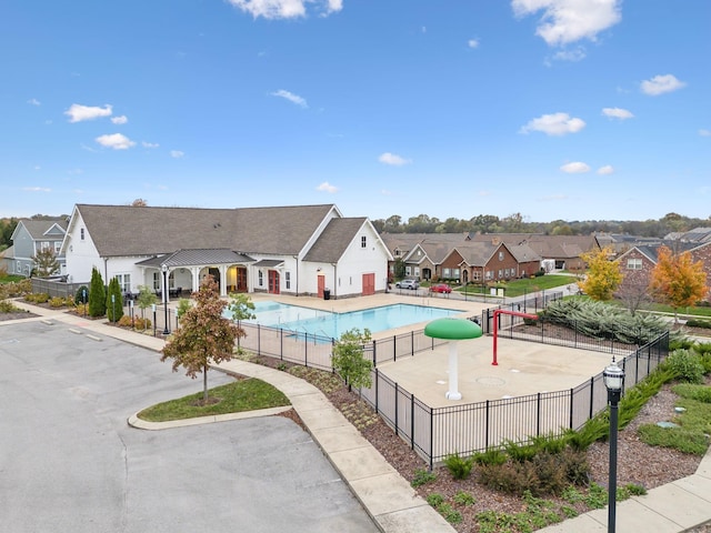 pool with a patio area, fence, and a residential view