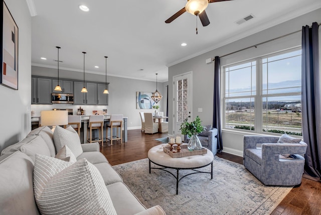 living area featuring visible vents, baseboards, dark wood-style floors, and crown molding