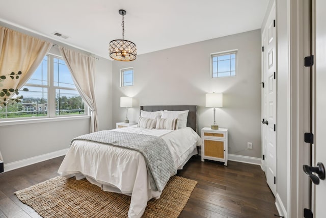 bedroom featuring dark wood-style floors, visible vents, a chandelier, and baseboards