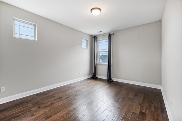 spare room with baseboards and dark wood-style flooring