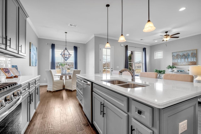 kitchen featuring visible vents, a sink, stainless steel appliances, gray cabinetry, and crown molding