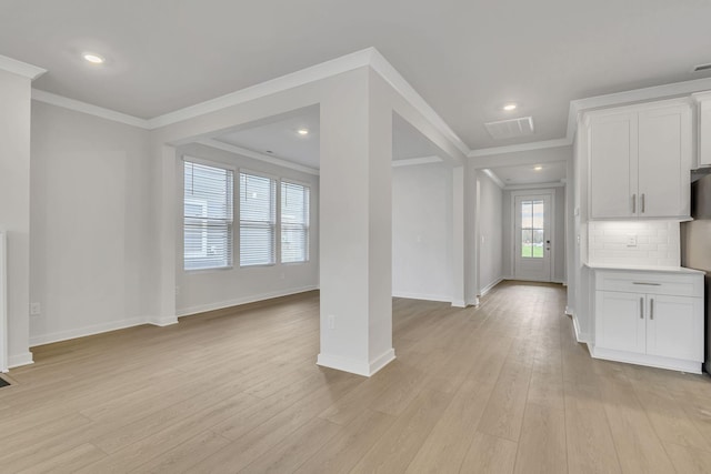 interior space featuring light wood finished floors, baseboards, white cabinets, ornamental molding, and backsplash